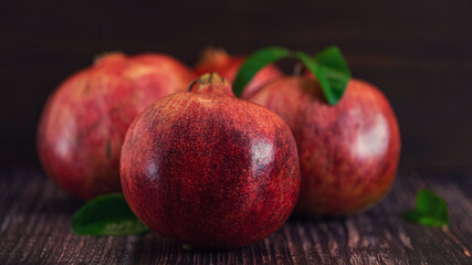 Fototapeta na wymiar Ripe pomegranate fruit with leaves on dark background