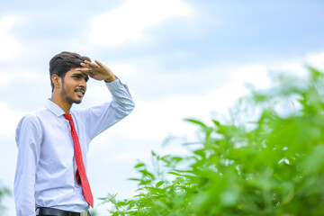 young indian agronomist standing at field and pointing direction