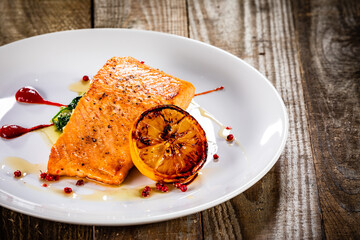 Fried salmon fillet with lemon served on wooden table 