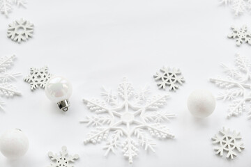 Pattern made of white balls and snowflakes on white background.