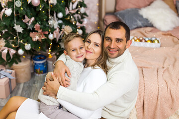 Beautiful family in knitted sweaters sitting near a Christmas