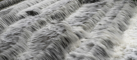 White Water flowing over weir low-level view at long exposure go give blurred motion effects