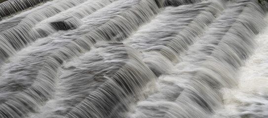 White Water flowing over weir low-level view at long exposure go give blurred motion effects