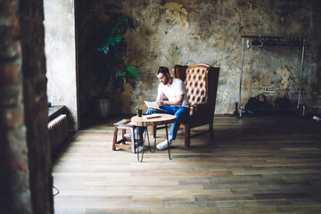 Fototapeta na wymiar Stylish man reading book in armchair