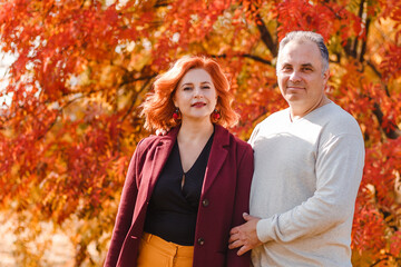 smiling man and middle-aged woman on beautiful autumn background
