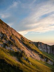 Sunset in the mountains. Mountain slope with rocks and grass,