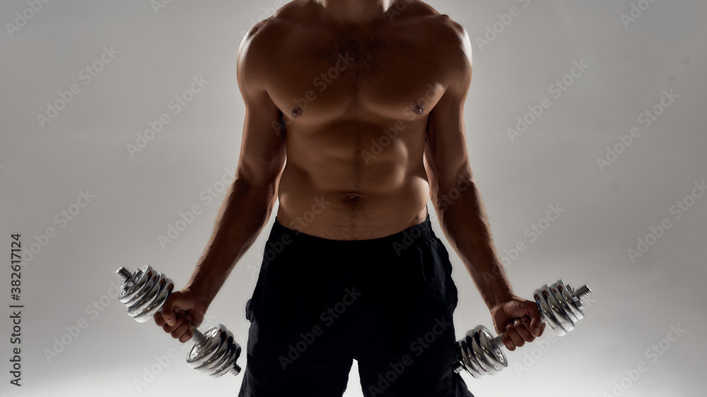 Wall mural Biceps Exercises. Cropped shot of a muscular caucasian man lifting weights while standing isolated over grey background