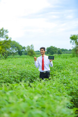 Technology and people concept, Young indian agronomist showing tablet at field