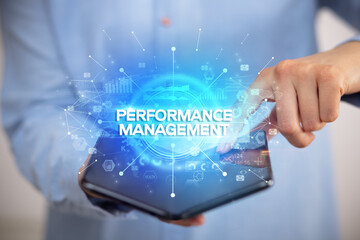 Businessman holding a foldable smartphone with PERFORMANCE MANAGEMENT inscription, new business concept