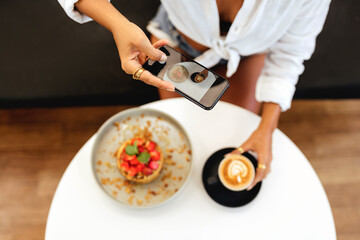 Woman taking a photo of breakfast with smartphone. Morning time.