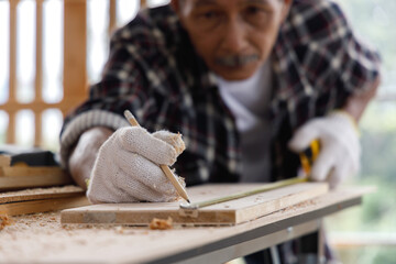 Senior man use tape measure to measure width of wood plank.