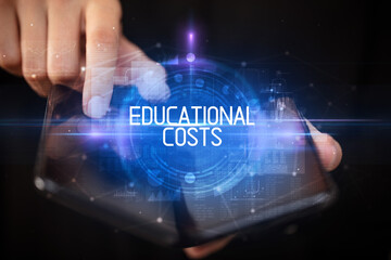 Fototapeta premium Young man holding a foldable smartphone with EDUCATIONAL COSTS inscription, educational concept
