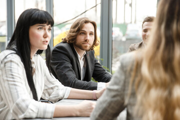 Meeting in progress. Two office workers are looking at their colleague with surpeise on their faces