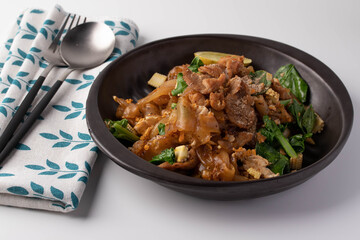 Soy sauce noodles with pork in a black plate