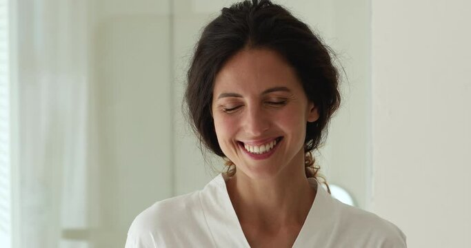 Close up head shot portrait 30s beautiful woman wear bathrobe smile look at camera. Gorgeous female with flawless face skin natural day make up and toothy white smile. Beauty care treatment ad concept