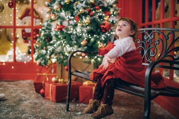 Obraz na płótnie Canvas Cute little boy in a red warm blanket near the New Year tree
