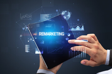 Businessman holding a foldable smartphone with REMARKETING inscription, successful business concept