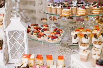 Sweet dessert cakes and cupcakes and jellys on the candy bar at the celebration