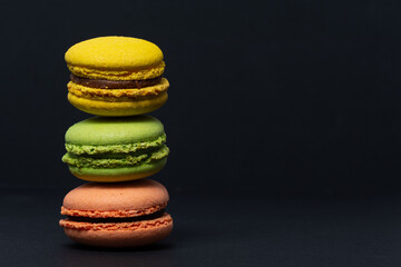 Macaroni of different colors stand one on top of the other in the form of a tower on a black background