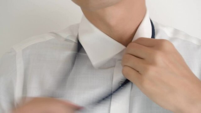 Exhausted Asian businessman loosen his fashionable blue knit tie and unbutton collar emotionally.