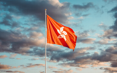 Beautiful flags of Hong Kong China waving against blue cloudy sunset sky background.