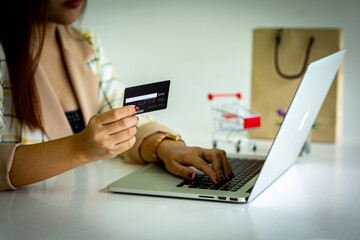 Asian woman hand using credit card and smartphone and laptop for buying online shopping payments
