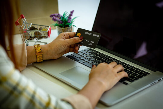 Asian woman hand using credit card and smartphone and laptop for buying online shopping payments