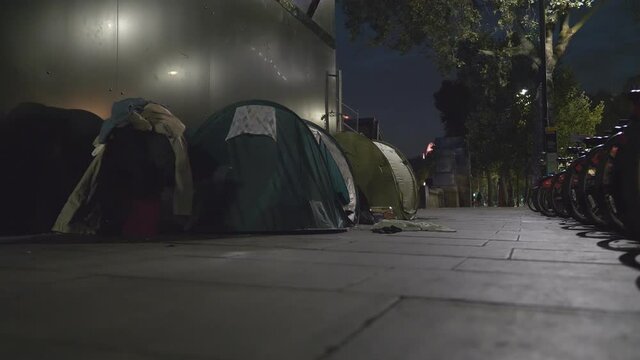 Homeless people in tents at night in a city.