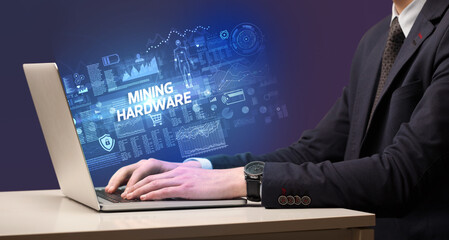 Fototapeta na wymiar Businessman working on laptop with MINING HARDWARE inscription, cyber technology concept