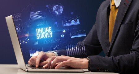 Businessman working on laptop with ONLINE SURVEY inscription, new business concept