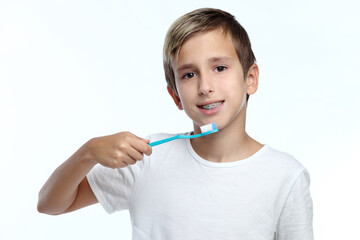 oy brushing his teeth with a toothbrush and looking at the camera isolated on white background