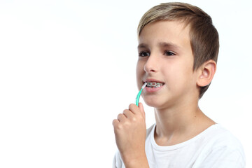 Guy with retainer for teeth brushing teeth on a white background.