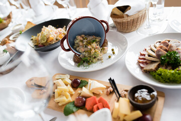 Table setting on which there is a cheese plate Russian salad and a meat plate