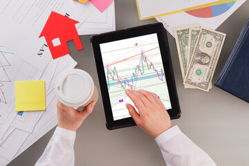 Young woman trader working at office. Graphs and charts on touch pads screen. Technology, finance and business marketing concept.