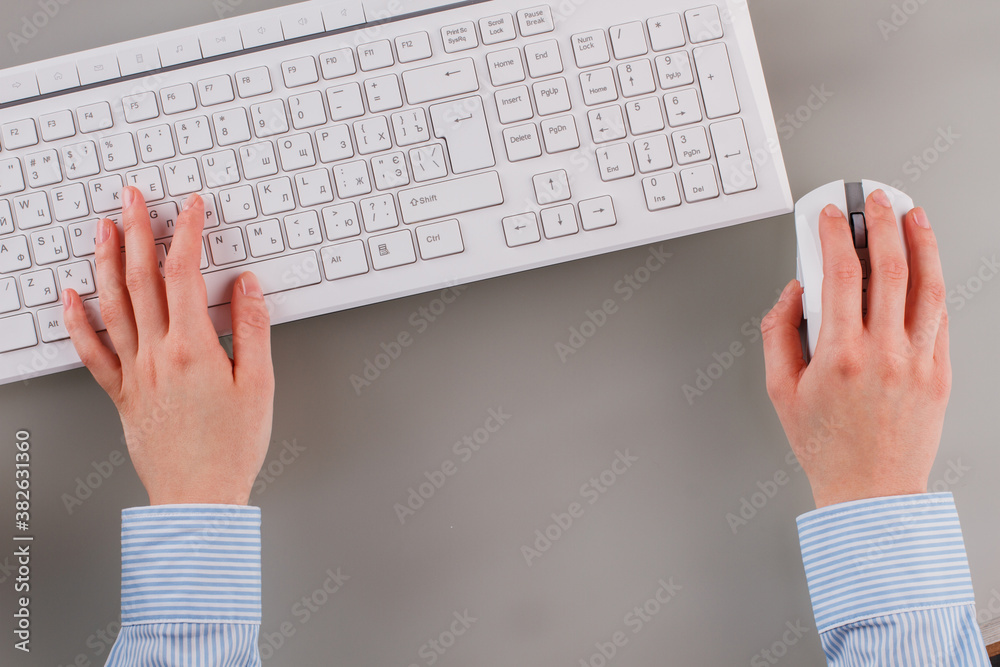 Wall mural close up hands of office woman working on keyboard. female hands in blue shirt holding computer mous