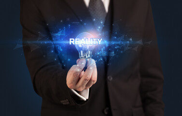 Businessman holding light bulb with REALITY inscription, innovative technology concept