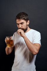 Man with a mug of beer in his hands emotions fun lifestyle white t-shirt dark isolated background