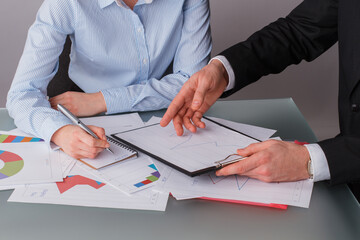 Business man and woman looking at company financial graphs. Business colleagues working with documents sitting at table in office.