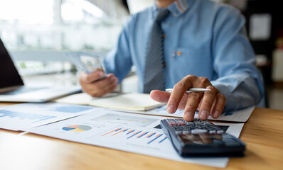 Businessmen use calculators to calculate budgets and analyze business profit growth. Financial...