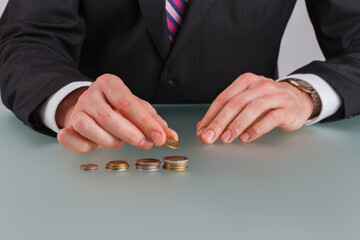 Businessman hand putting coins on table. Finance, investment, savings and banking concept.