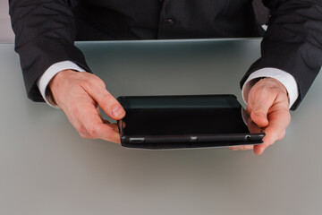Businessman holding digital tablet at meeting. Close up businessman hands using computer tablet while sitting at table.