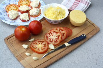 Fresh tomatoes and garlic on a cutting board.Tomato appetizer with cheese and garlic.
