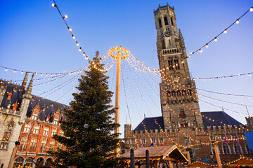 Naklejka premium Traditional Christmas market in Europe, Bruges, Belgium. Main town square with decorated tree and lights. Christmas fair concept