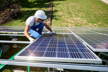 Professional worker installing solar panels on the green metal construction, using different...