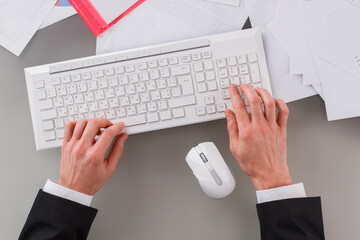 Businessman working on keyboard sitting at table. Male hands typing on computer keyboard.