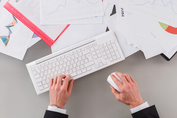 Caucasian businessman working at office. Male hands working with computer keyboard and documents on the table.