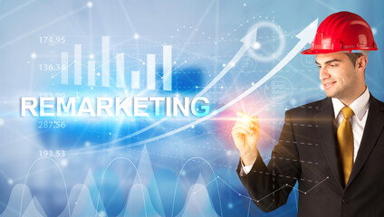 Young businessman with helmet drawing REMARKETING inscription, modern business technology concept
