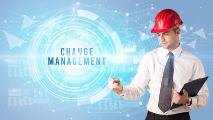 Handsome businessman with helmet drawing CHANGE MANAGEMENT inscription, contruction business concept