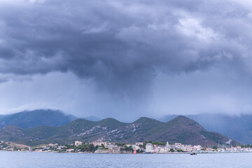A dark cloud pouring rain over the village of Saint Florent . Corsica
