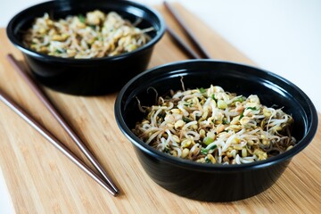 Close up black bowls with traditional Chinese sprouts salad. Healthy vegetarian eating. Green sprouts salad. Chinese cuisine.